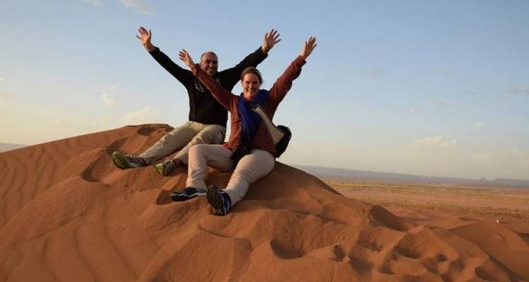 Stel dat hun armen in vreugde omhoogsteekt bovenop een roestbruine zandduinen in de Sahara woestijn