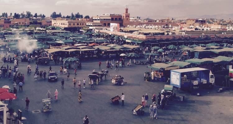 Panoramisch uitzicht over het bruisende marktplein Jemaa el-Fna met eetstalletjes en opstijgende rook
