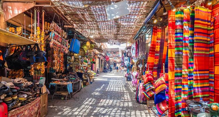 Colorful market alley with textiles and goods.
