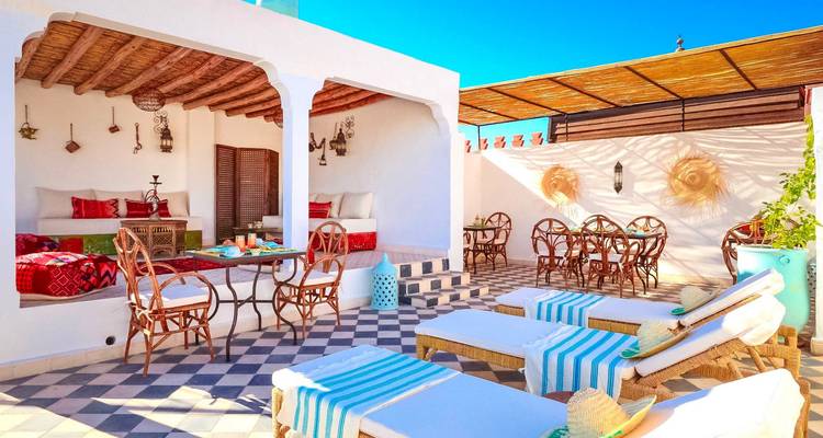 Sunny rooftop terrace with loungers and seating.