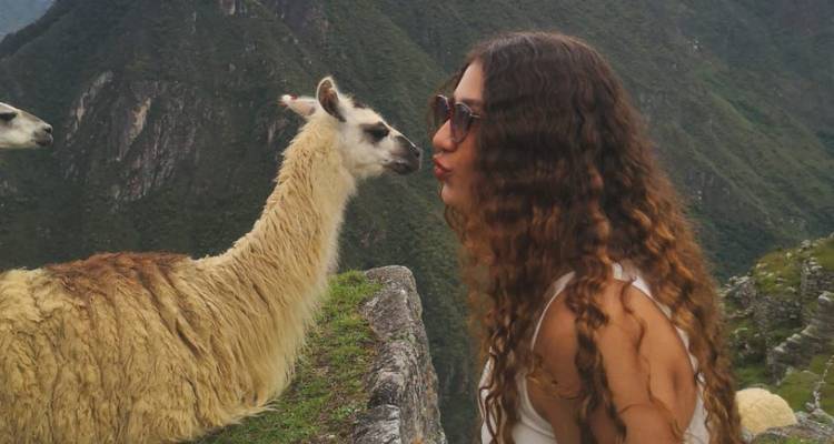 Femme embrassant un lama à un belvédère panoramique.
