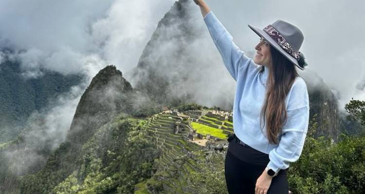Femme posant avec le Machu Picchu au loin.