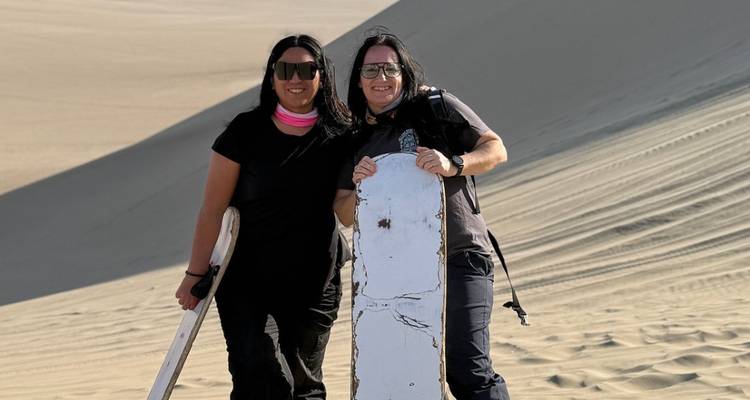 Deux femmes avec des planches de sable dans un désert.