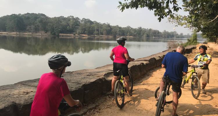 Ciclistas descansando junto a un río sereno.