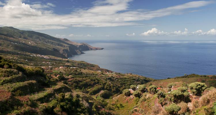 Panoramablick auf eine Küstenlandschaft mit sanften Hügeln und Meer.