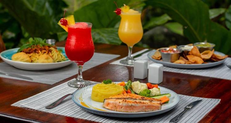 Un délicieux repas servi sur une table avec des boissons colorées et un feuillage luxuriant tout autour.