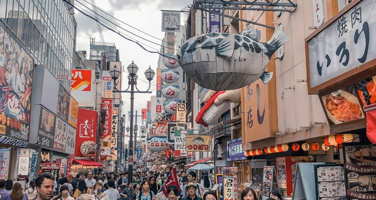 Busy street with people and gigantic food-themed decorations on buildings.