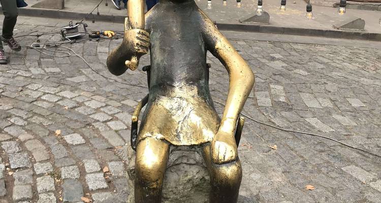 Sculpture en bronze d'une figure assise dans un espace public.