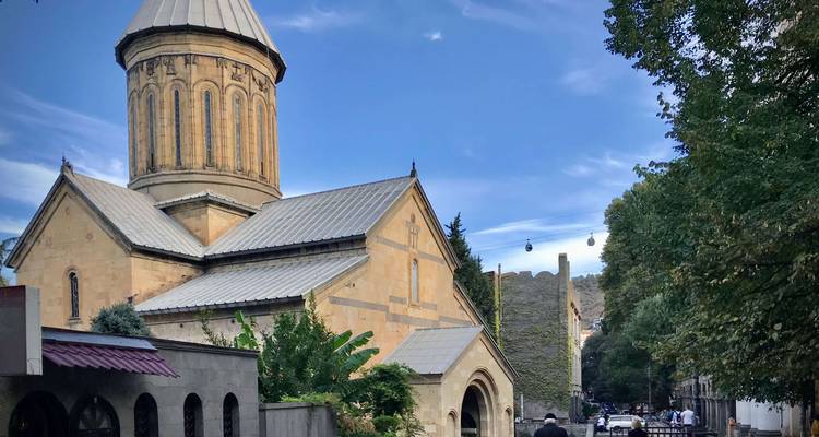 A church with a bell tower surrounded by trees and ancient walls.