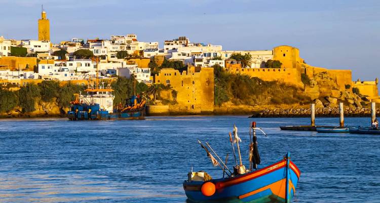Kleurrijke visserboot op het water met een schilderachtig uitzicht op historische gebouwen en fort.