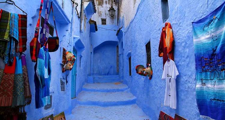 Blauwe voetgangersstraat omzoomd met kleurrijke textielstoffen en traditionele gebouwen.