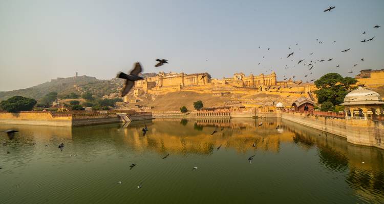 Eine majestätische Festung mit Spiegelung in einem See, umgeben von Vögeln.