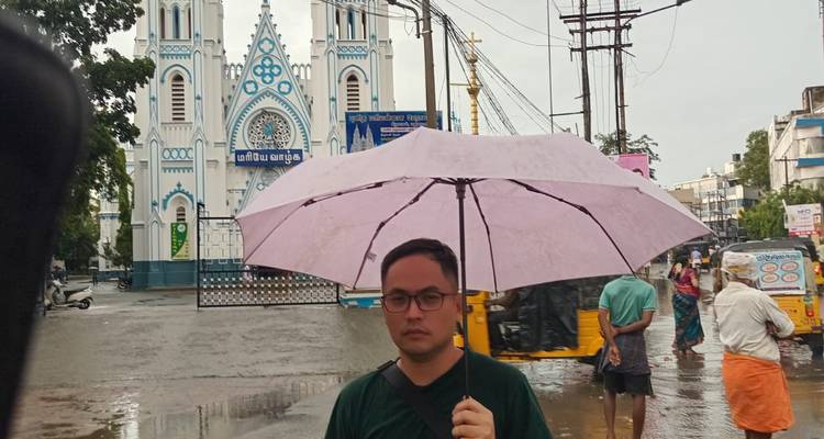 Una persona sosteniendo un paraguas frente a un edificio de iglesia en un día lluvioso.