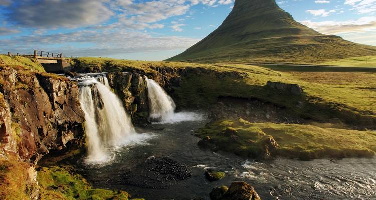 Waterfall flowing beside a distinctive mountain peak.