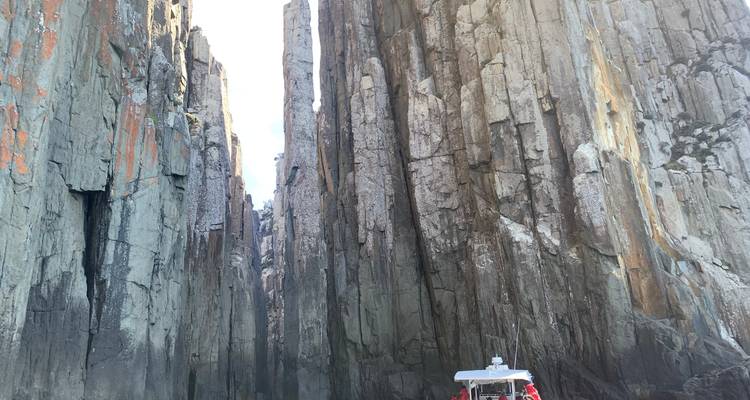 Boat navigating between tall cliffs.