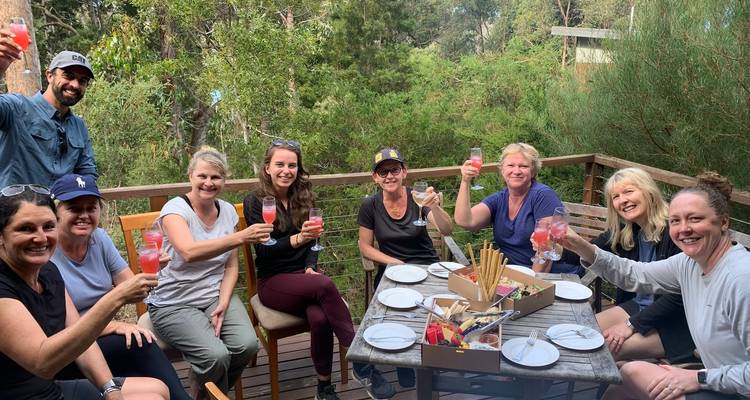 Group of people enjoying drinks on a patio surrounded by forest.