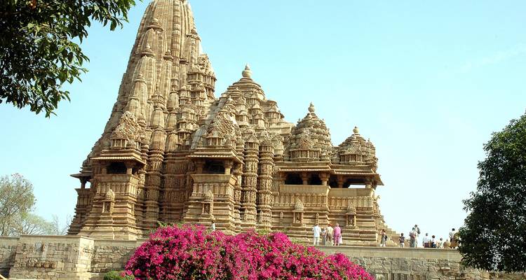 Majestätischer Tempel mit blumigem Vordergrund und Touristen beim Erkunden.