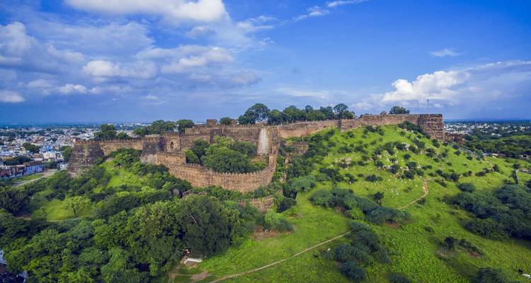 Large fort surrounded by greenery with city in the distance.