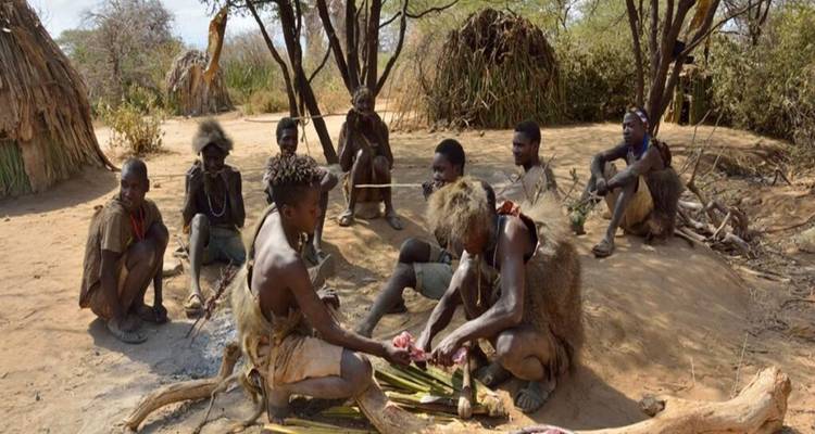 Eine Gruppe von Personen, die in einer traditionellen Umgebung sitzt und wahrscheinlich kocht oder Essen zubereitet.