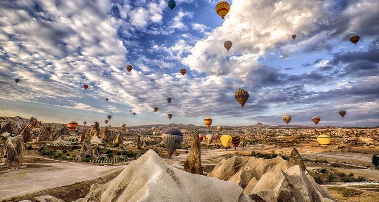 Hot air balloons over rocky landscapes at sunrise.