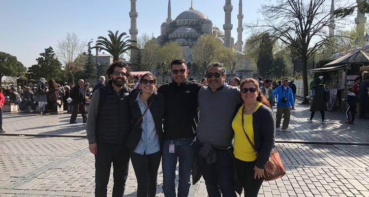 Group of people smiling for a photo in front of an iconic mosque.