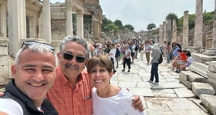 A crowd walking through ancient ruins with weathered stone columns and pathways.