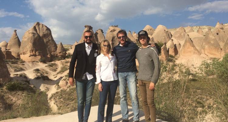 Four friends in a rocky landscape posing for a photo under the sky.