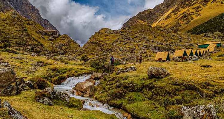 Schilderachtige vallei met tenten en een stromende beek.