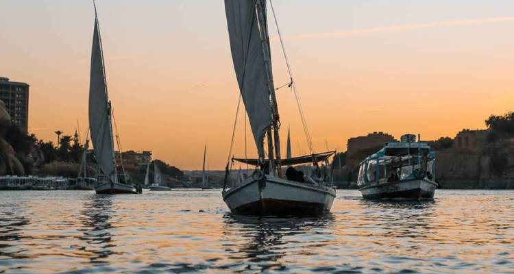 Sailboats on a river during sunset.