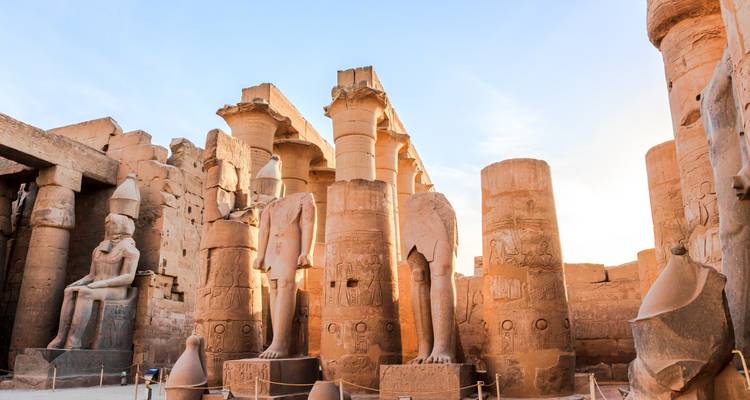 Ancient Egyptian ruins with statues and columns.