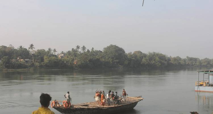 Menschen überqueren einen Fluss auf einem Bambusfloss.