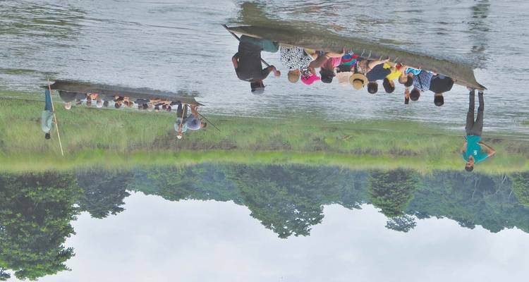 Turistas en botes tradicionales disfrutando de una vista serena del río.