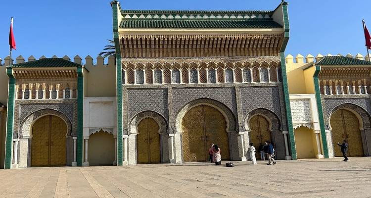Puerta del palacio real en Fes con mosaicos ornamentados y arcos de herradura, turistas tomando fotos