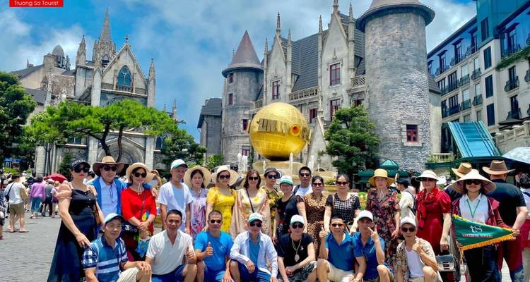 Large group of tourists in front of castle-like buildings and a large gold globe.