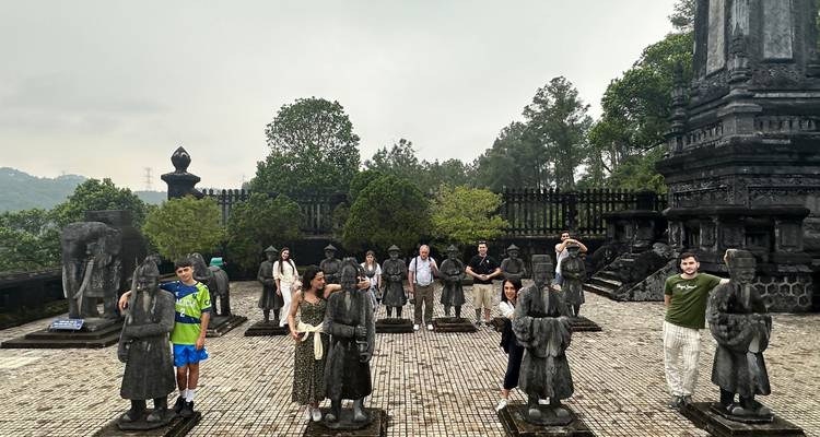Group of people posing among stone statues in a historical site.