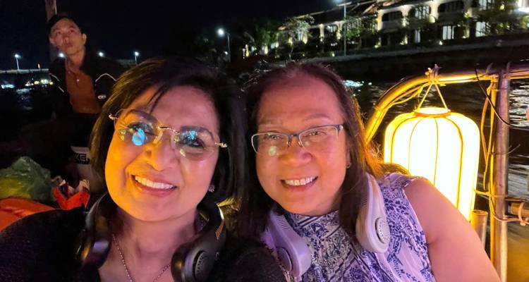 selfie de deux femmes lors d'une balade en bateau à lanternes la nuit avec les lumières de la rivière en arrière-plan
