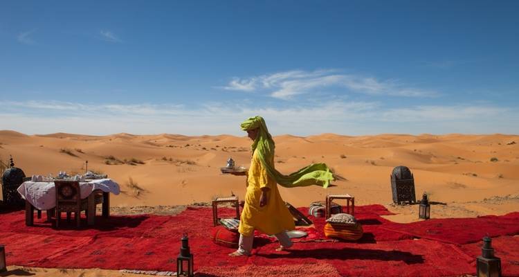 Person walking across a setup in the desert with a blue sky.