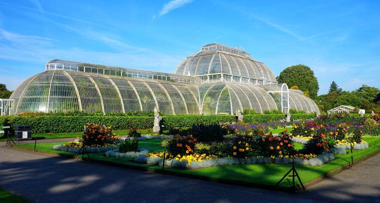 Invernadero en jardín botánico con arriates de flores.