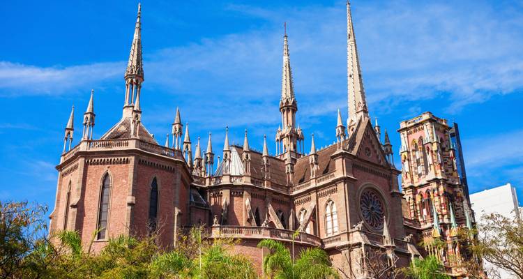 Catedral con agujas de detalles intrincados contra un cielo azul despejado.