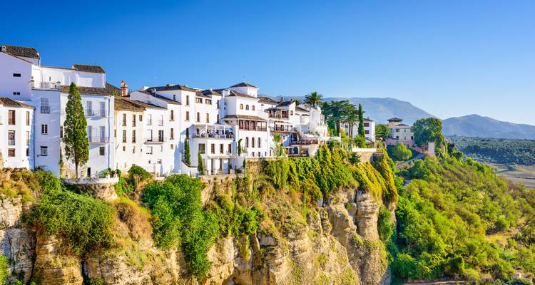 Edificios encalados en un acantilado con vistas panorámicas del campo.