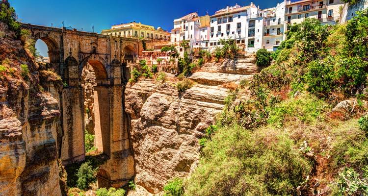 Puente espectacular que atraviesa un desfiladero profundo con un pueblo histórico en los acantilados.