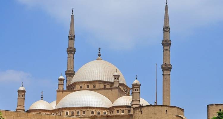 Moschee mit mehreren Minaretten vor blauem Himmel.