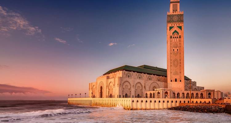 Hassan-II-Moschee bei Sonnenuntergang mit Meereswellen in Casablanca.