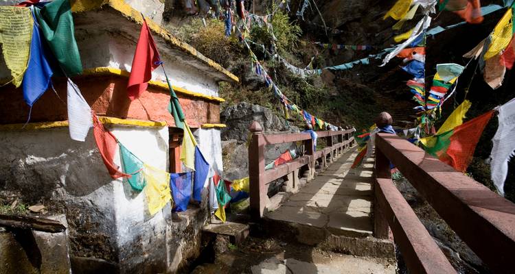Footpath with prayer flags against a rocky hillside.