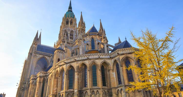 Imposante gotische kathedraal met hoge spitsen en steunbogen die prachtig afsteken tegen een helderblauwe lucht.