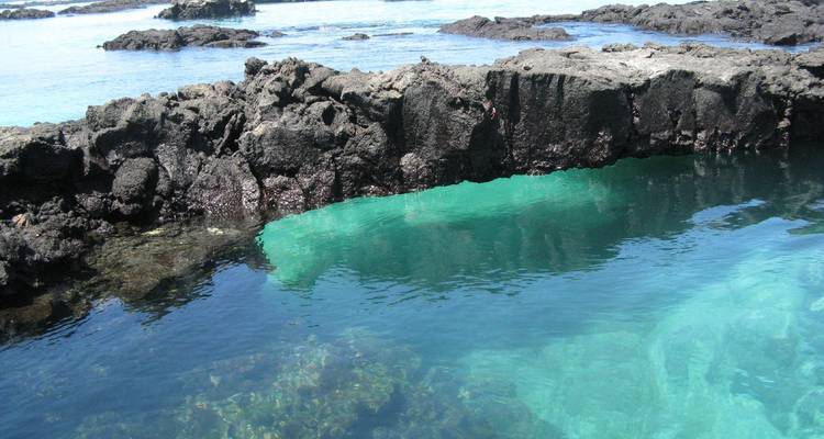 Felsige Küste mit klarem, blauem Wasser.