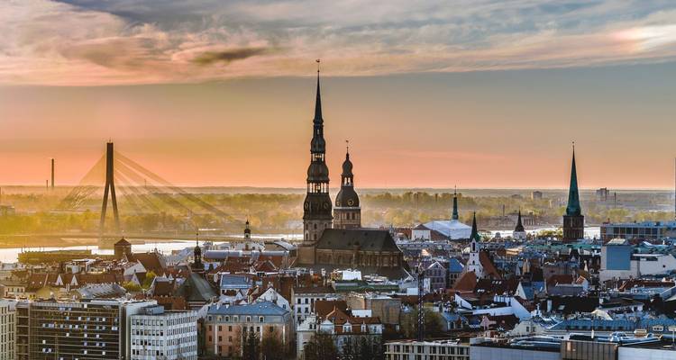 Sonnenaufgang über Rigas Skyline mit mittelalterlichen Kirchtuermen und der Bruecke ueber die Daugava.