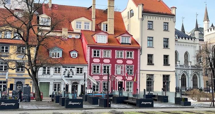 Reihe farbenfroher historischer Häuser mit roten Dächern und Außencafés in Rigas Altstadt.