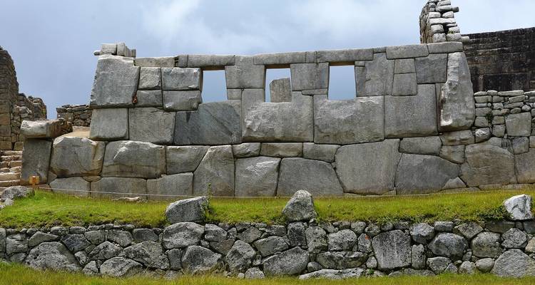 Stenen muren van Machu Picchu met grasrijke omgeving.