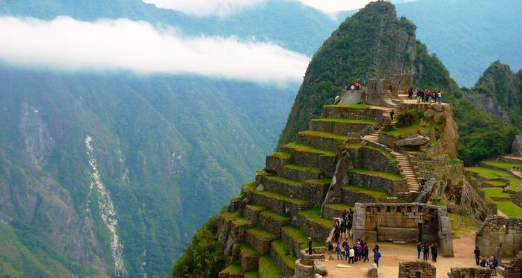 Mensen die wandelen op de terrassen van Machu Picchu met uitzicht op de bergen.